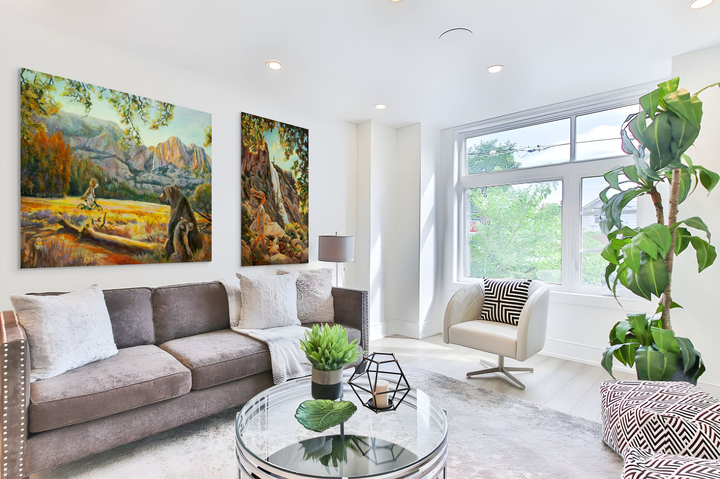 Modern living room with a gray sofa and large windows, featuring original fine art paintings from Yosemite Valley in warm yellow and orange tones.