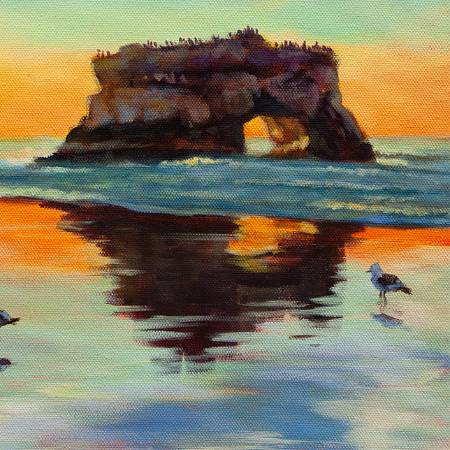 Detail of natural rock arch and coastal cliff at Santa Cruz beach in warm sunset light.