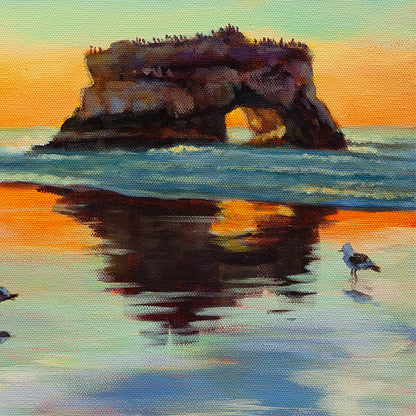 Detail of natural rock arch and coastal cliff at Santa Cruz beach in warm sunset light.