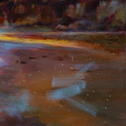 Detail of wet sand reflecting orange and gold sunset light at Santa Cruz Dog Beach.