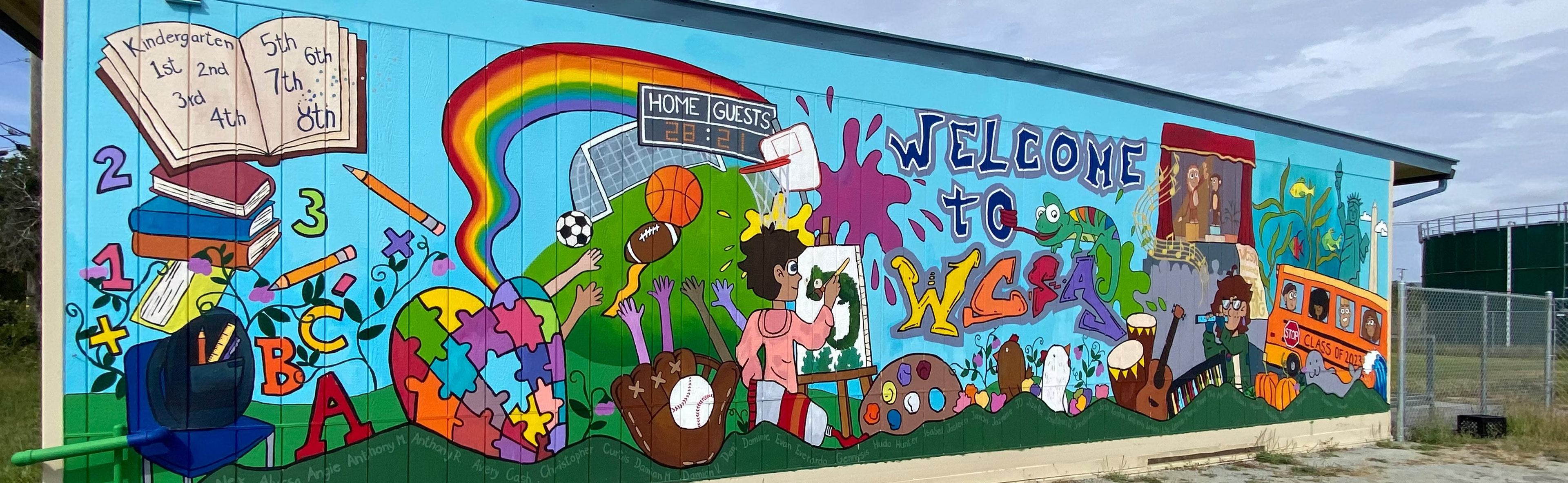 Colorful mural on a building wall with text Welcome to WCSA and various illustrations.