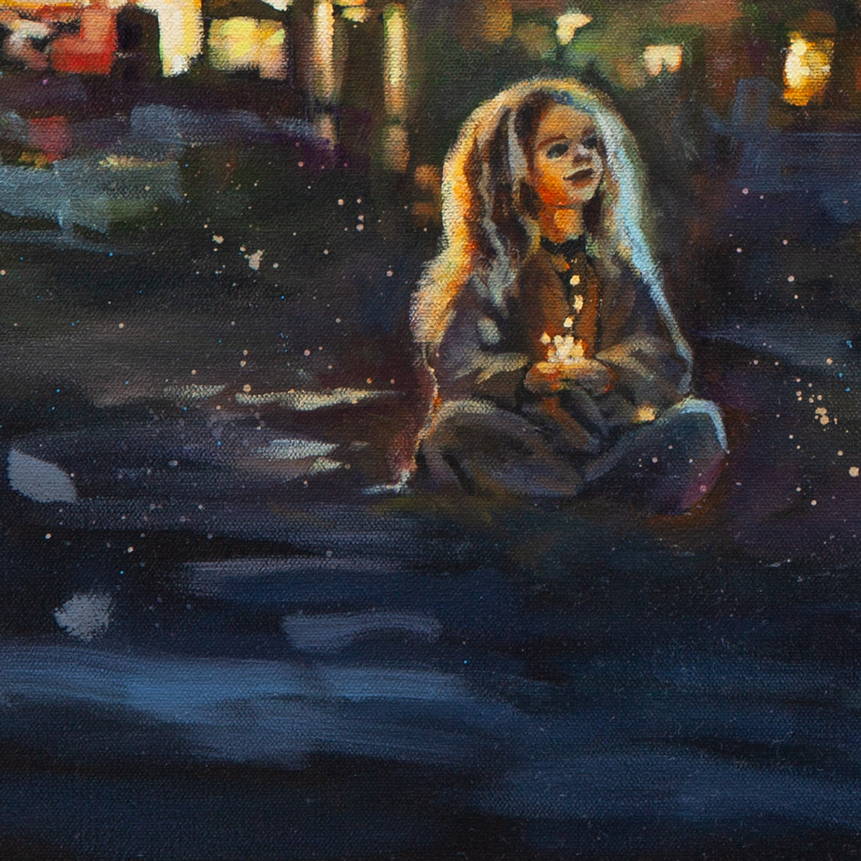 Close-up of a girl sitting on the beach holding light in her palms, orange glow on her face and hair, blue foreground strokes, lights behind.
