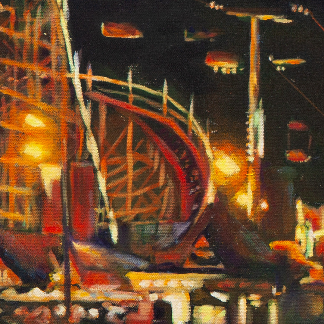 Detail of the Giant Dipper roller coaster glowing yellow and orange with red supports and sky ride cars against a dark night sky.