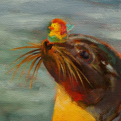 Detail of the seal’s golden-brown head balancing a mermaid duck with red hair and green tail from Balancing Act, coastal painting by Martina Goulart.