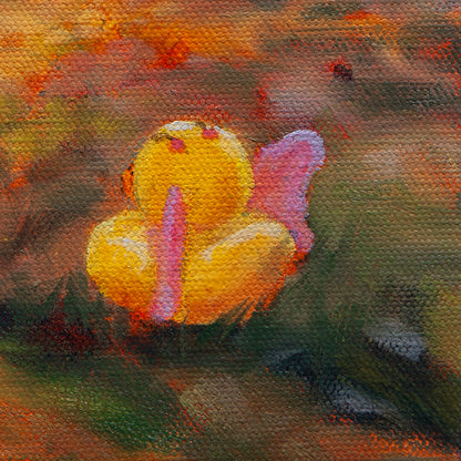 Close-up of a yellow-orange rubber duck with pink wings resting in golden grass under sunlight from Curious Exchange by Martina Goulart.