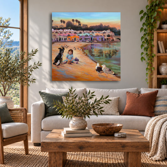 Colorful Capitola Village fine art print featuring a child and dog playing on the beach near the iconic colorful beachfront houses in Capitola, California, displayed above a sofa in a warm, sunlit coastal living room with natural wood furniture and inviting neutral decor.
