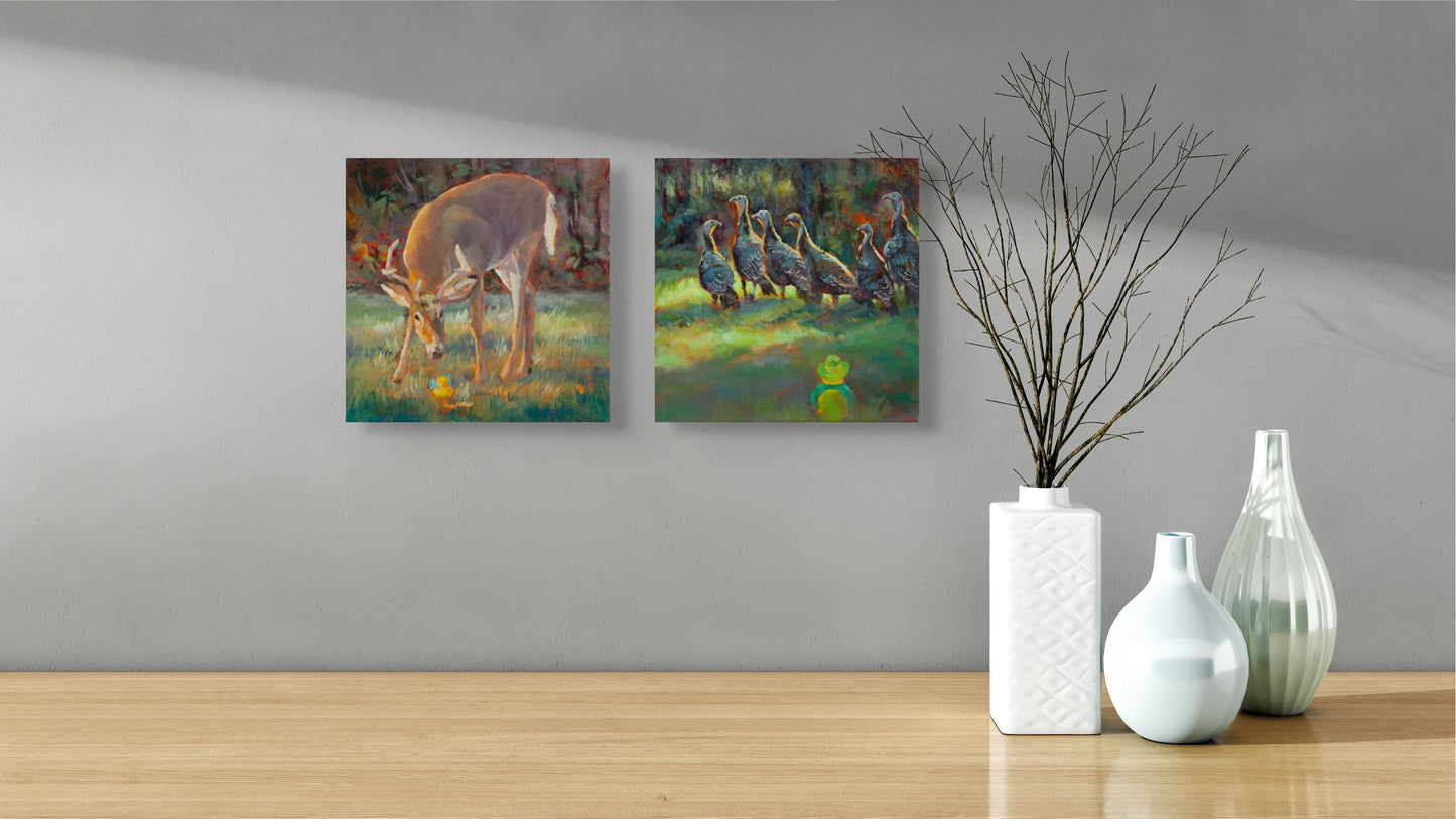 Two Wild Neighbors paintings — deer and turkeys — hanging above a brown table with three modern white vases, one holding a twig.