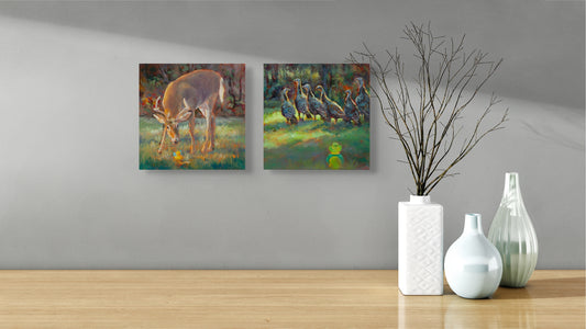 Two Wild Neighbors paintings — deer and turkeys — hanging above a brown table with three modern white vases, one holding a twig.