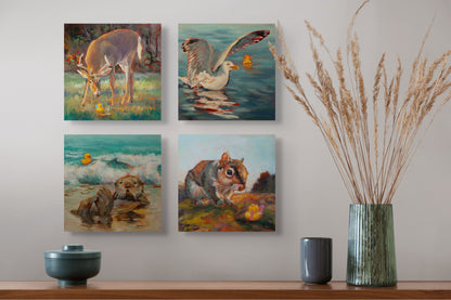Four Wild Neighbors paintings — deer, seagull, otter, and squirrel — hanging above a brown table with a green vase, yellow grass, and two gray cups.