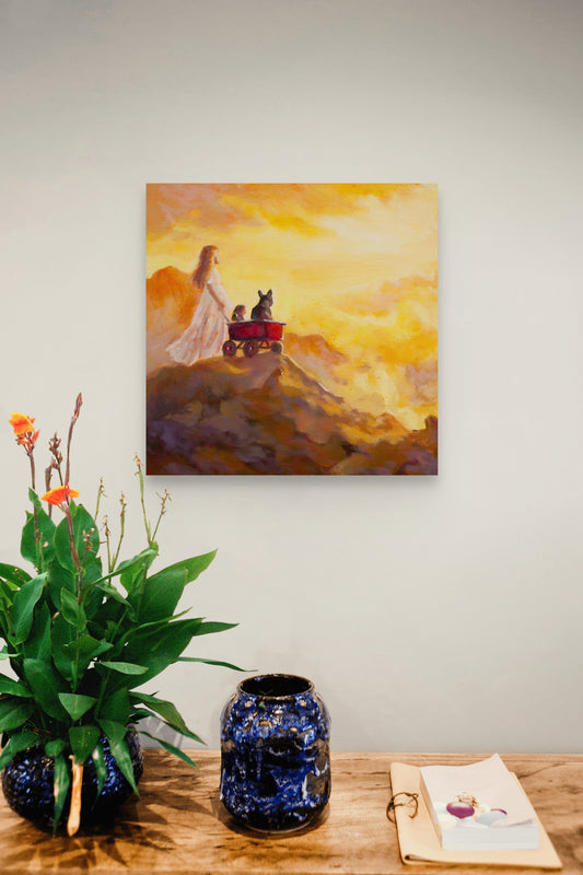 Painting of a girl pulling a red wagon with two animals at sunrise, hanging above a wooden table with a blue ceramic vase and greenery.
