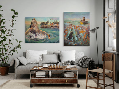 Two large coastal paintings hanging above a sofa: one of a girl in a paper boat beside a breaching whale, and the other of a boy fishing above a kelp forest with a seal.