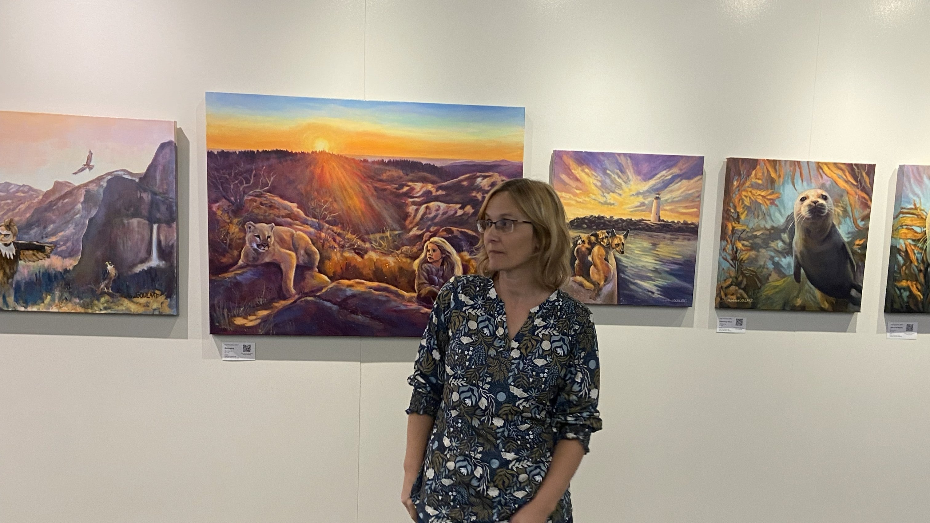 woman standing in front of a wall with colorful paintings.