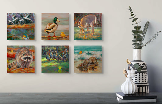 Six Wild Neighbors paintings — raccoons, mallard, deer, turkeys, and otter — hanging above a gray table with white and black vases and a green plant.