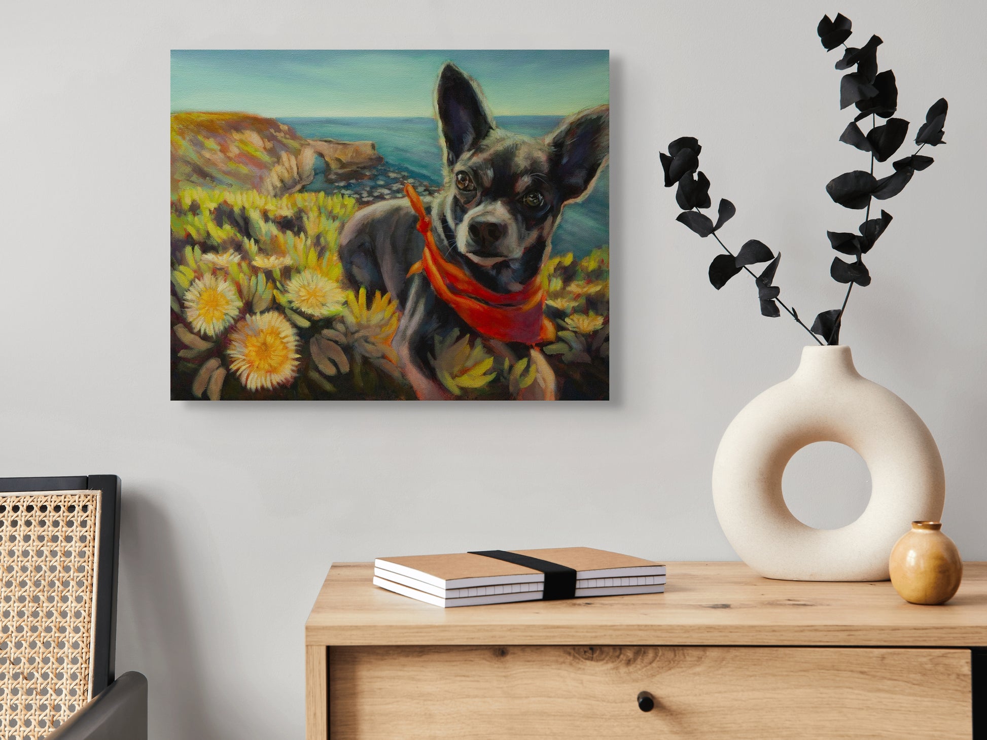 Original dog painting Picture Perfect hanging above a side table with a modern white vase and green plant, coastal artwork by Martina Goulart.