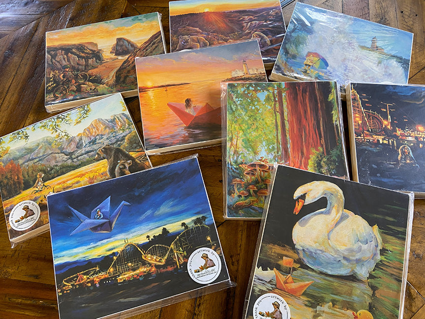 Fine art prints by Martina Goulart displayed on a wooden table, showing colorful storytelling paintings mounted on cradle wood panels, ready to hang wall art