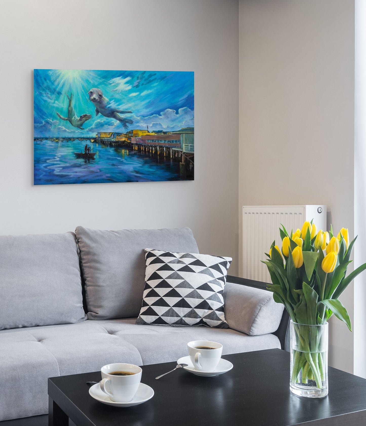Living room with gray sofa and coffee table, featuring original California fine art of seals near Monterey Pier in soft blue and purple tones