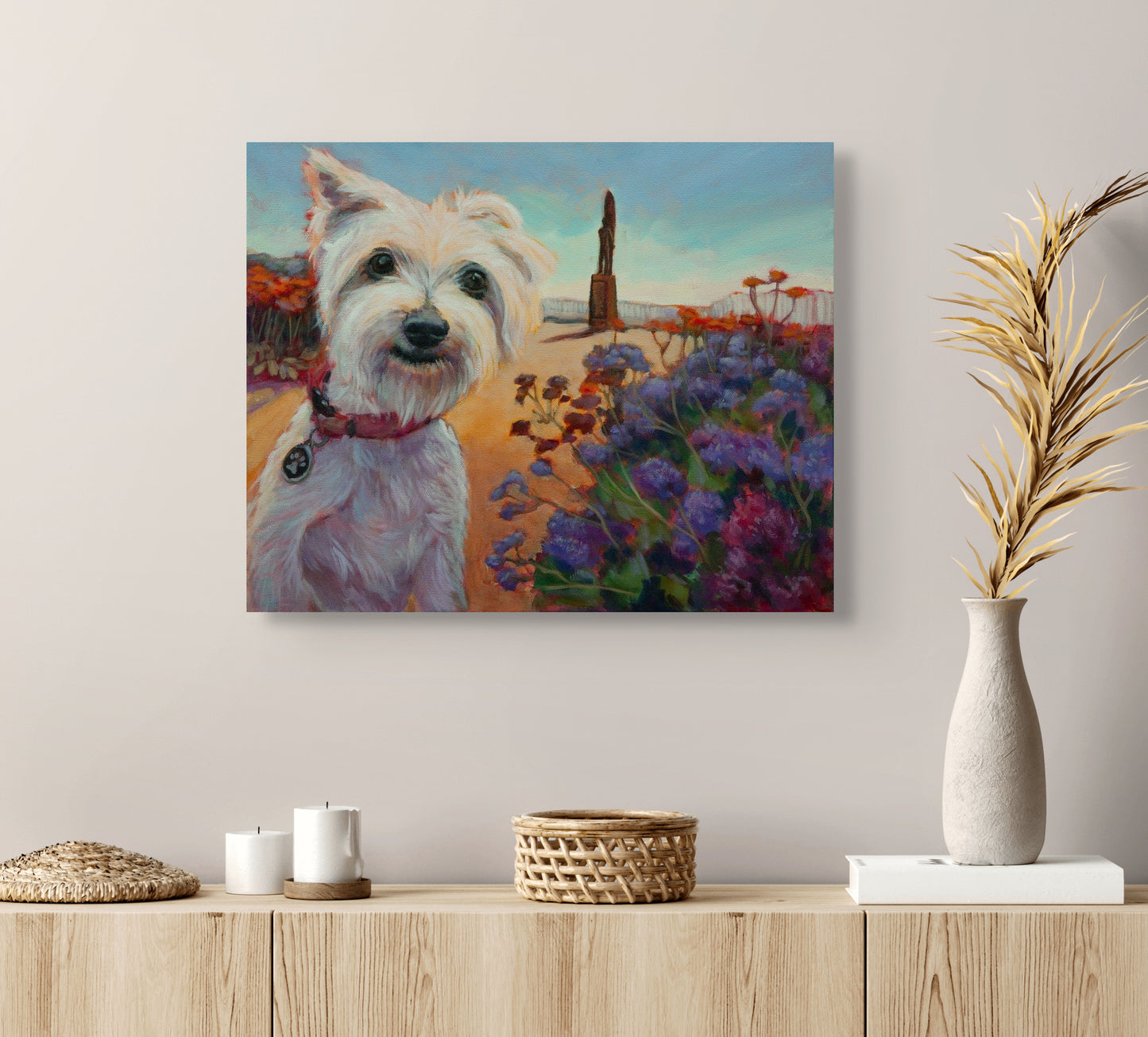 Original dog painting Surfer’s Best Friend hanging above a natural wood cabinet with white vase, tan plant, candles, and wicker bowl, by Martina Goulart.