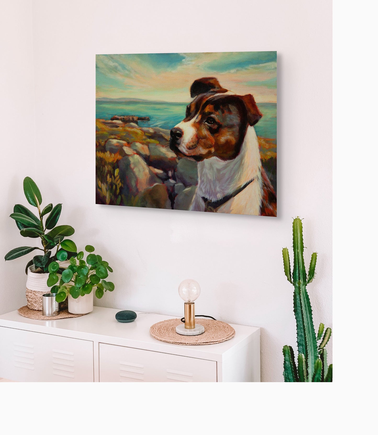 Original dog painting The Watchful One hanging above a white cabinet with green plants, coastal artwork from West Cliff Santa Cruz by Martina Goulart.