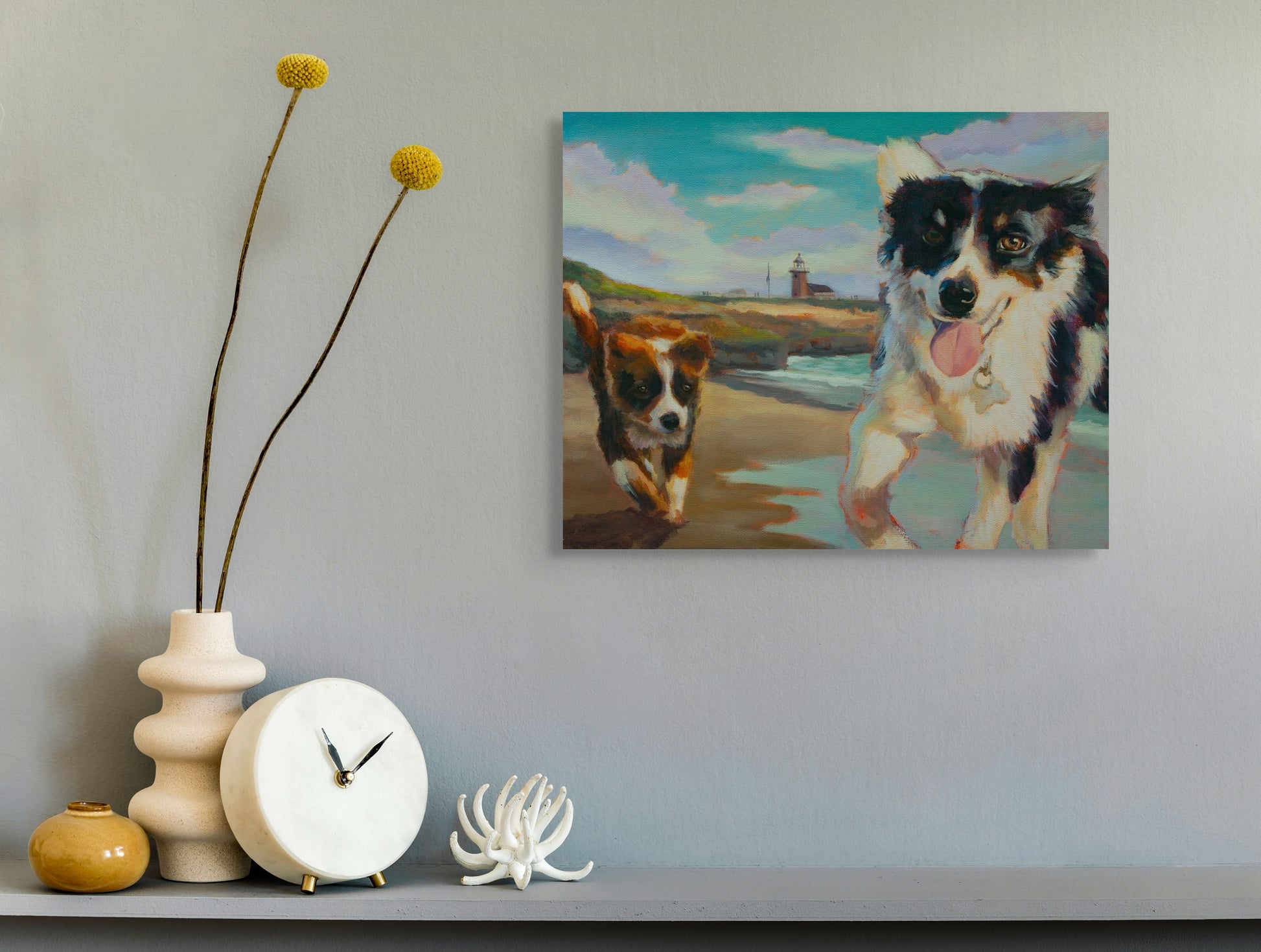 Original dog painting from the Santa Cruz coast series hanging above a side table with a vase, clock, and seashell, artwork by Martina Goulart.
