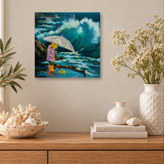 Colorful coastal art print featuring a child with an umbrella and yellow rubber ducks facing a dramatic ocean wave, displayed above a wooden cabinet with seashells and white ceramic vases in a sunlit beach-inspired room.