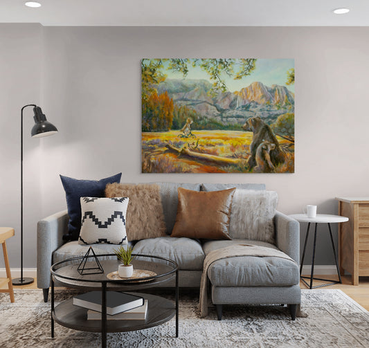 Painting Wearing the Wild hanging above a light gray couch with brown pillows, glass round coffee table, and neutral cozy living room decor.