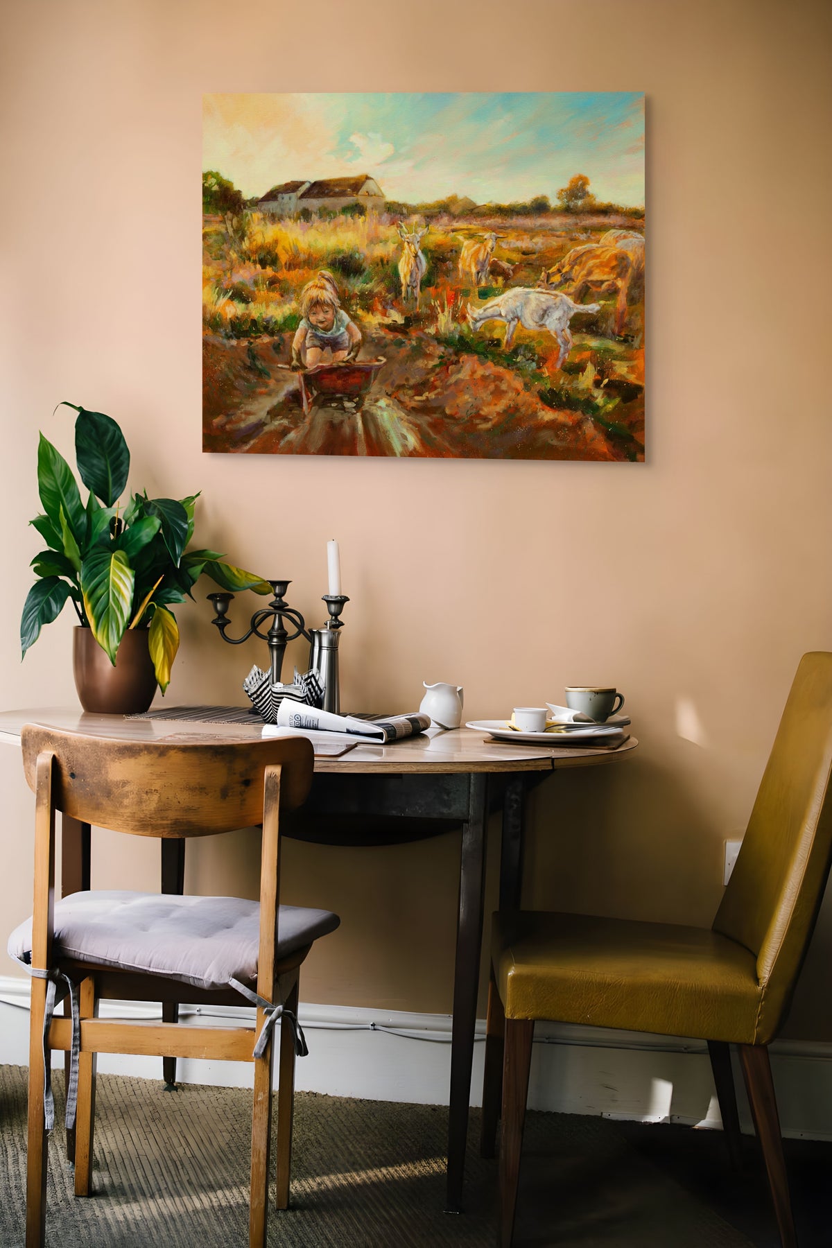 Painting Working Hard hanging on a brown wall above wood table with two chairs, houseplant, plate, cup, and newspaper in a warm, rustic room.